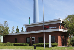 Billedet viser Toften Varmeværk, en rød murstensbygning i to forskudte etager og med en høj hvid skorsten.